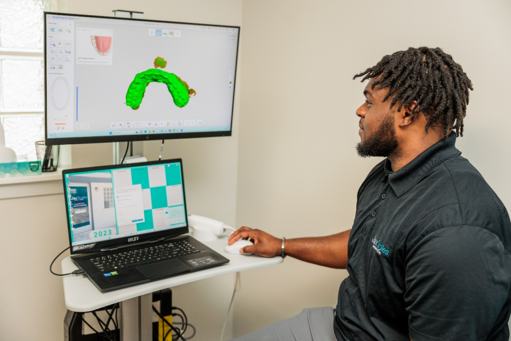 A dentist at Jax Smiles Dentistry working on a jaw model on a computer