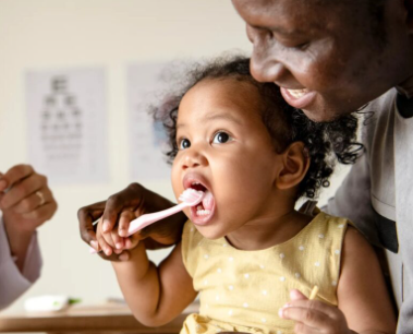 A father teaching his daughter how to brush properly.