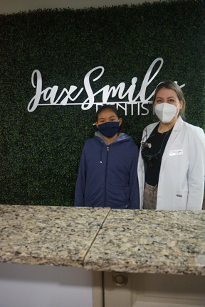 An Adolescent Standing with a Jacksonville Dentist at the Jax Smiles Dentistry Welcome Desk