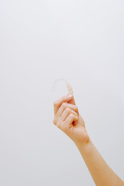 An image of a hand holding a clear aligner