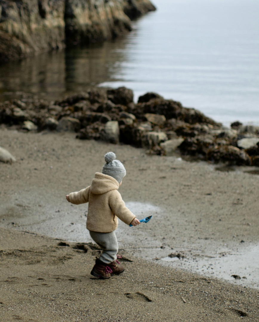 A healthy child playing on a sandy shore.